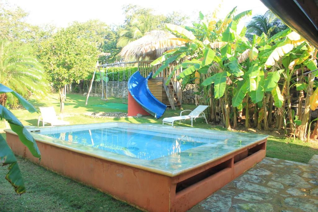 a swimming pool with a slide and a playground at Gipsy Ranch Rooms in Cabarete