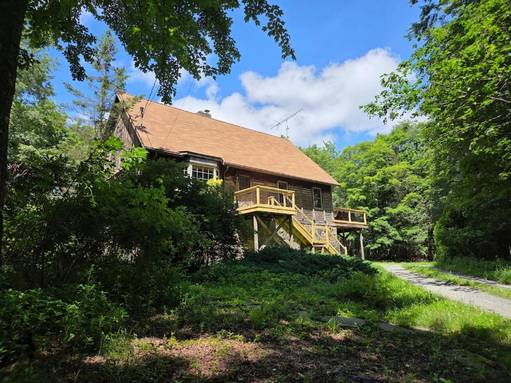 a large wooden house with a deck in the woods at Highlands Hideaway - Secluded 4BR Forest Gem in Chemung