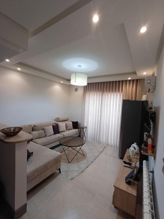 a living room with a couch and a tv at Le charment in Sukrah