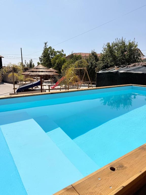 a large blue swimming pool with a wooden deck at Encantos da Aldeia - Casa da Pedra in Oliveira de Azemeis