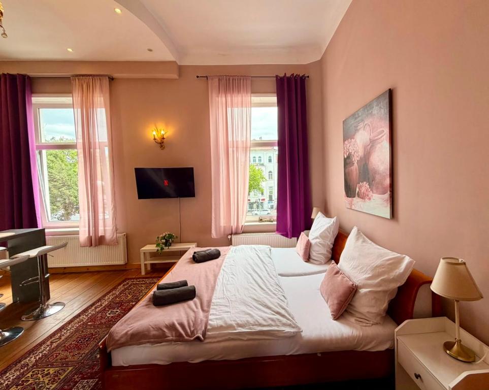 a bedroom with a large bed with pink walls and windows at Royal Rose Suite in zentraler Lage in Bremen