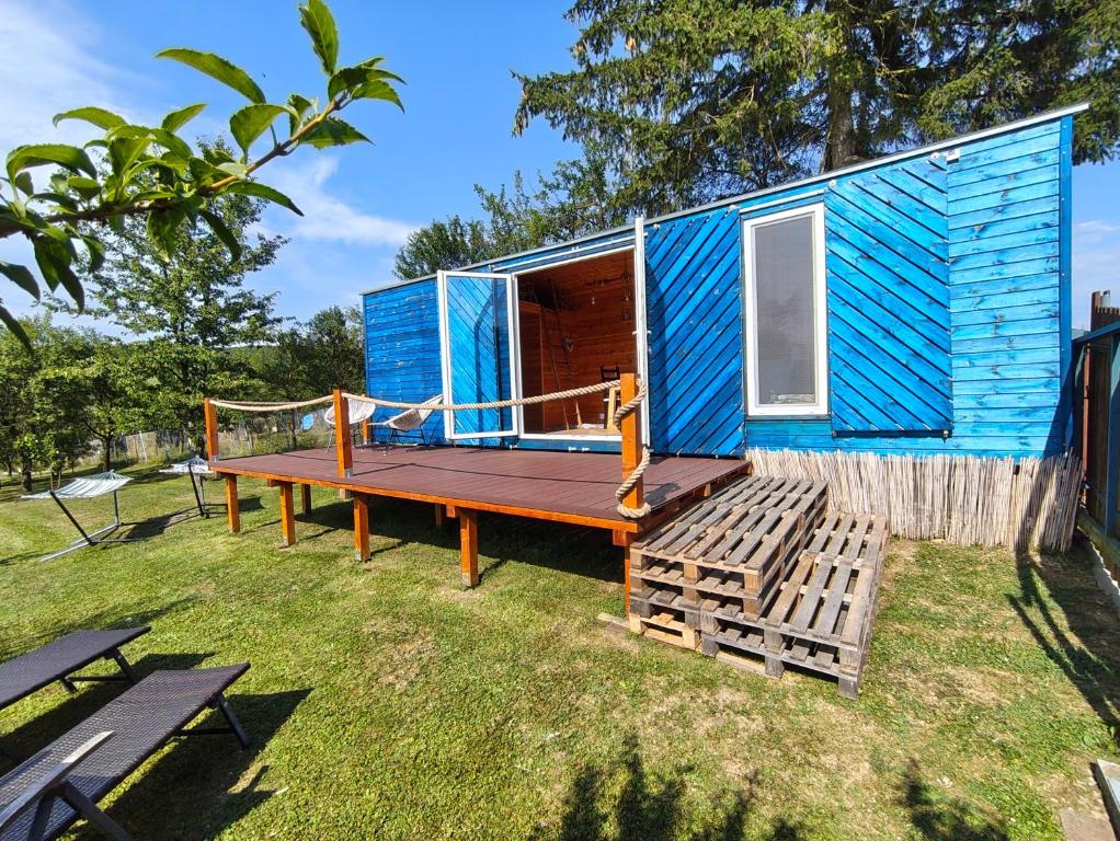 a blue tiny house with a wooden porch and a deck at Slovácká maringotka in Šumice