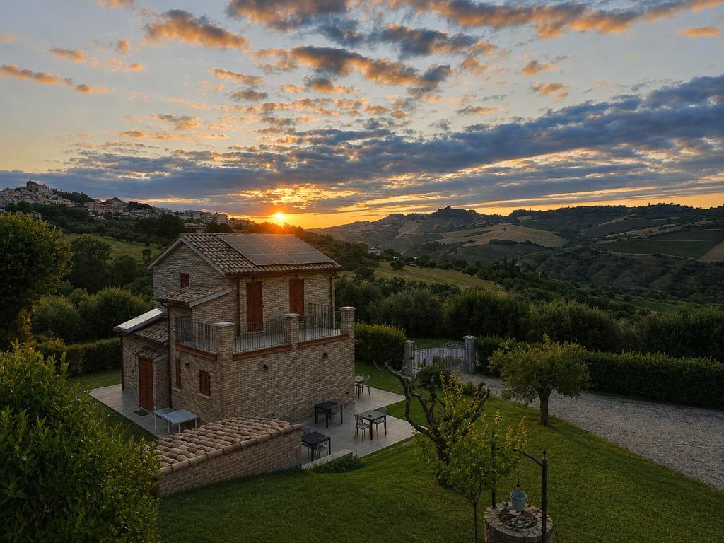 an old building with the sunset in the background at Casale Parvil in Monteprandone