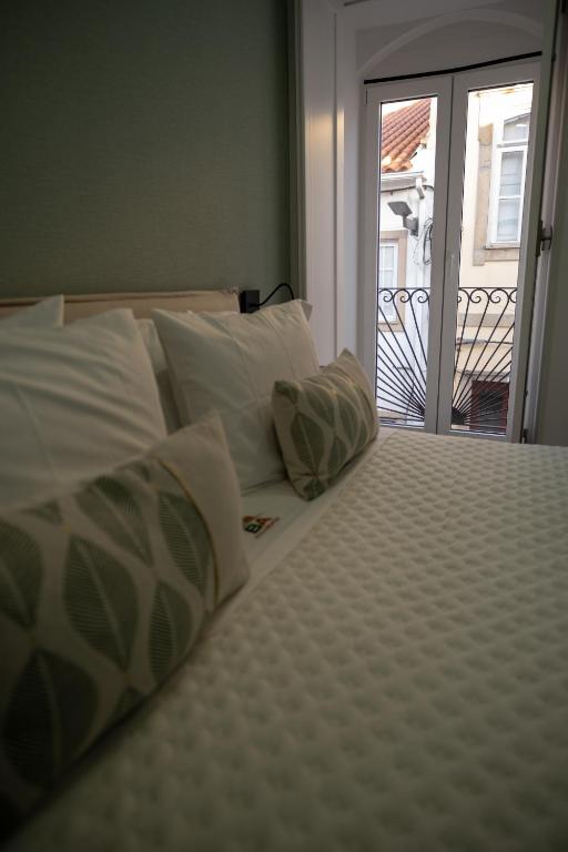 a bed with white pillows and a view of a balcony at Côa River Apartment in Vila Nova de Foz Coa