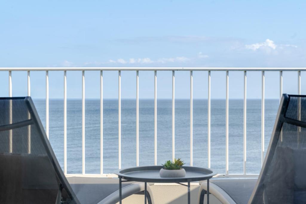 a balcony with a table and chairs and the ocean at Casa Rosa Panoramic Seaview in Lagoa