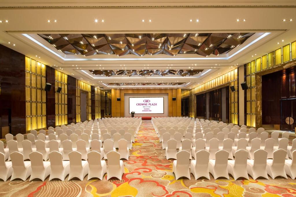 an empty hall with white chairs and a projection screen at Crowne Plaza Taizhou by IHG in Taizhou