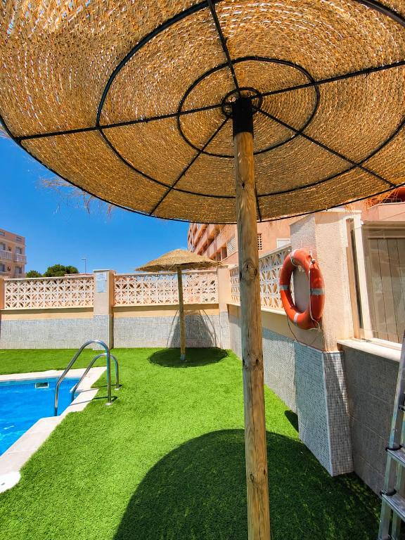 a large straw umbrella sitting on top of a yard at Ático Cassinello Roquetas in Roquetas de Mar