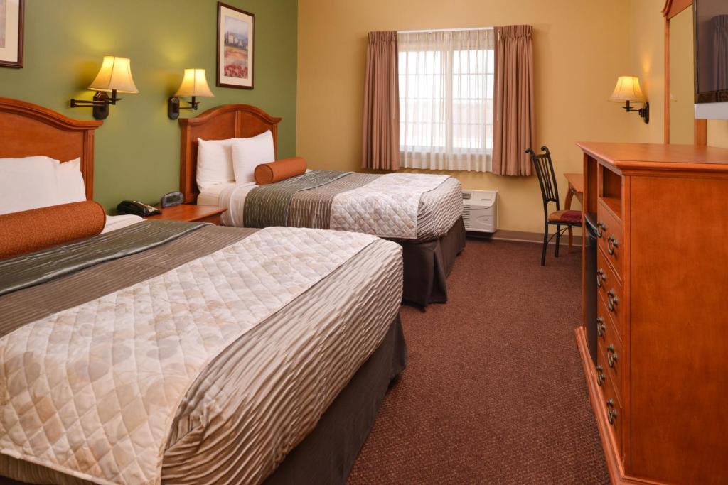 een hotelkamer met 2 bedden en een dressoir bij Country Hearth Inn & Suites Edwardsville in Edwardsville