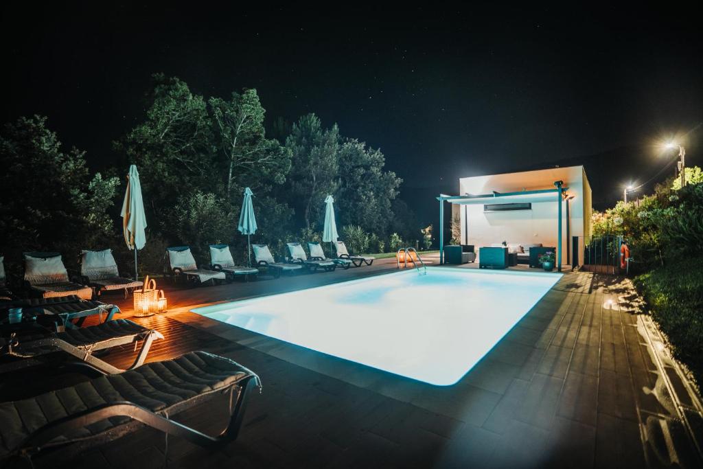 a large pool with chairs and umbrellas at night at Casas Peralta - Outeiro in Arouca