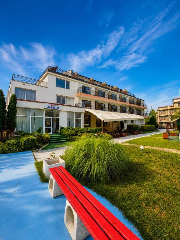 a red bench in front of a building at Hotel Jasmine in Byala