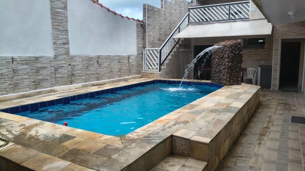 a swimming pool with a waterfall in a house at Linda casa Edícula "fundos do terreno" com piscina in Itanhaém