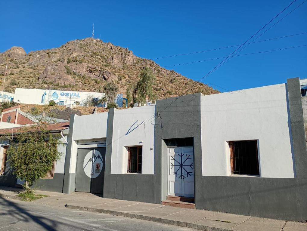 a white building with blue doors and a mountain at Hostal Casona del Canto in Los Andes