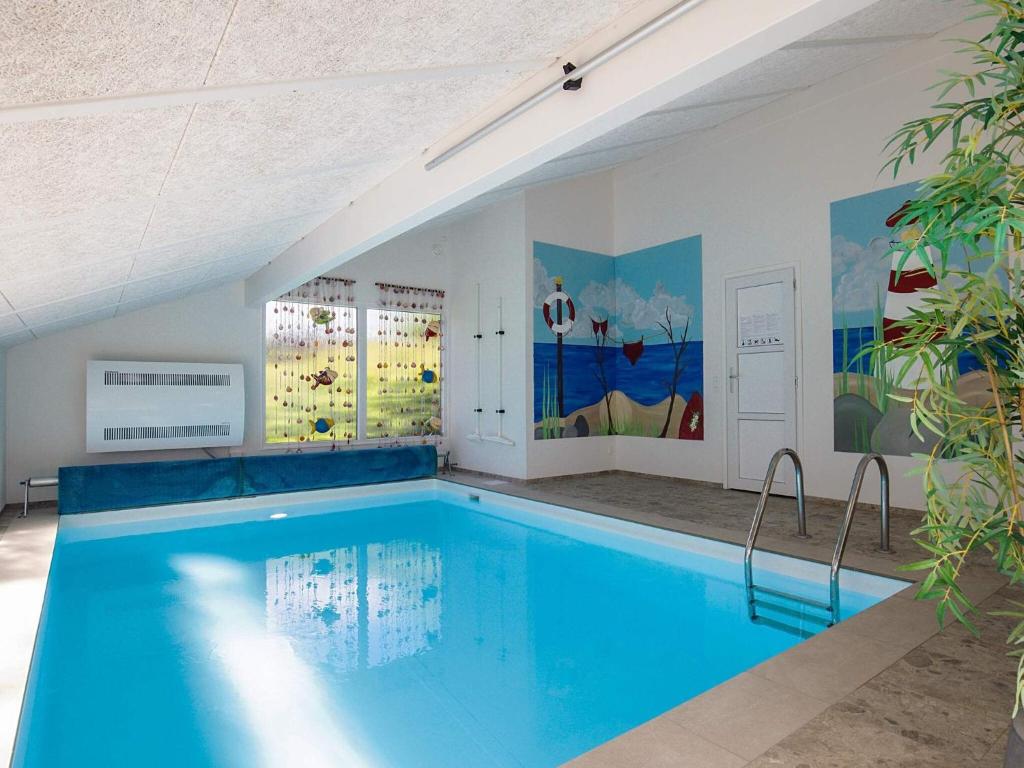 a swimming pool with blue water in a building at 5 star holiday home in Bindslev in Bindslev