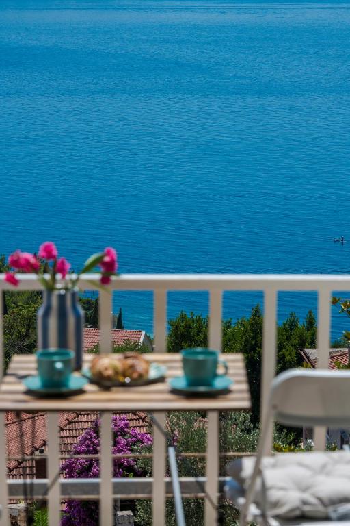 a table with a vase of flowers on a balcony overlooking the ocean at Room Blue View in Mlini