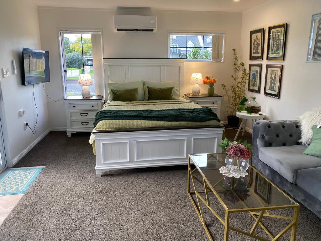 a bedroom with a large bed and a couch at Wattle Downs Palm Beach Studio in Auckland