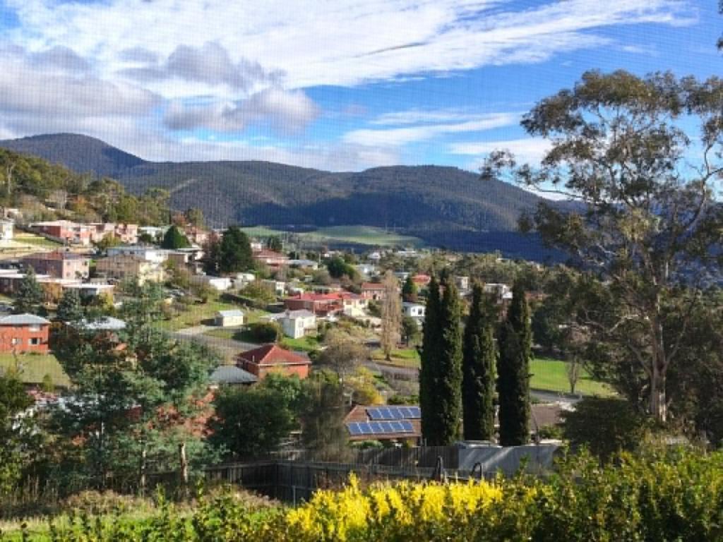 a view of a town with trees and mountains at Enkindled Haven in Moonah