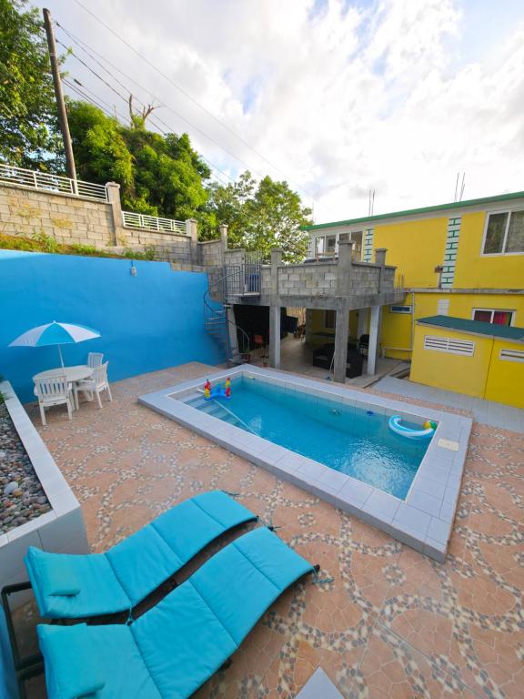 a swimming pool in a yard with a yellow building at Barefoot Apartments in Roseau