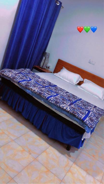 a bedroom with a bed with a blue curtain at Abronoma Guest House in Ogbojo