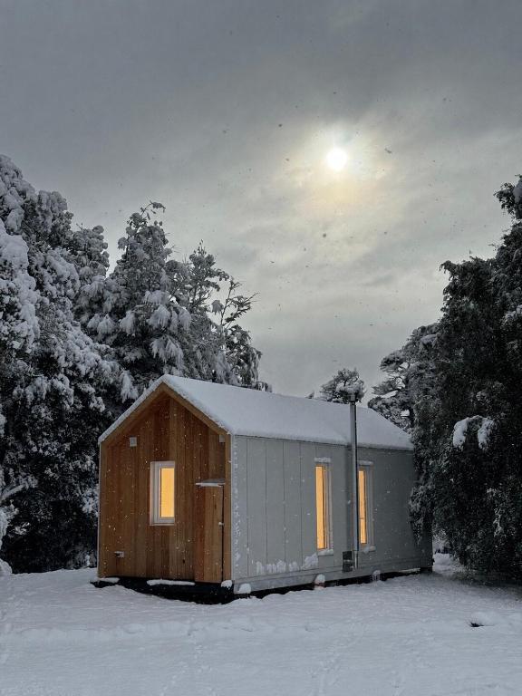 eine kleine Hütte im Schnee, der Mond am Himmel in der Unterkunft LANÍN Tiny House in San Martín de los Andes