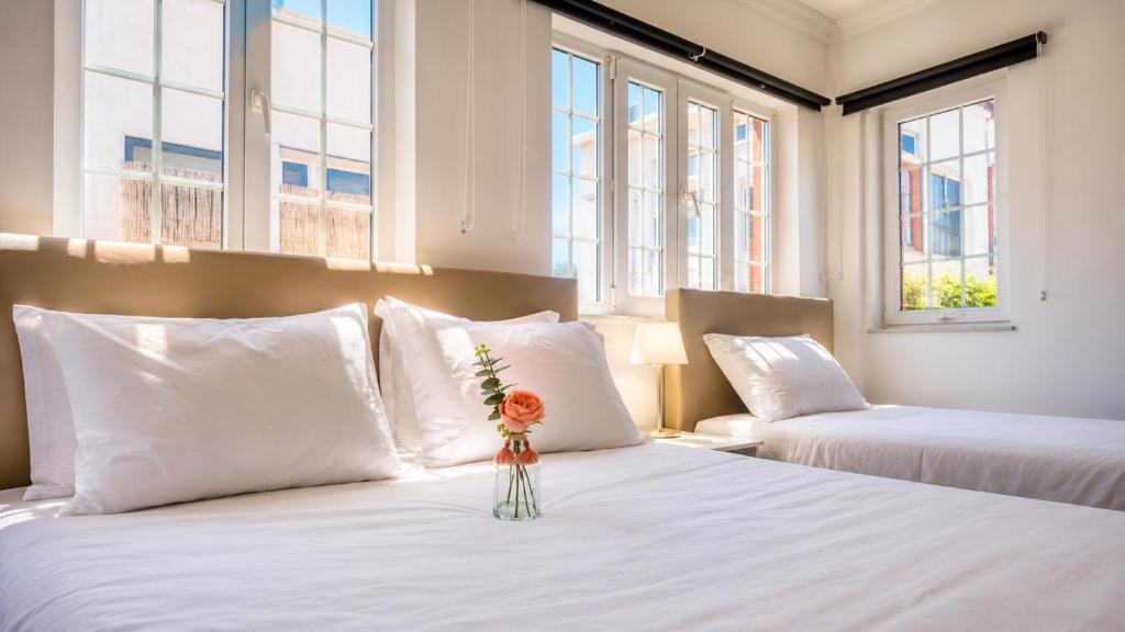 a bedroom with two beds with a vase with a flower on it at Vila Olivença in Costa da Caparica