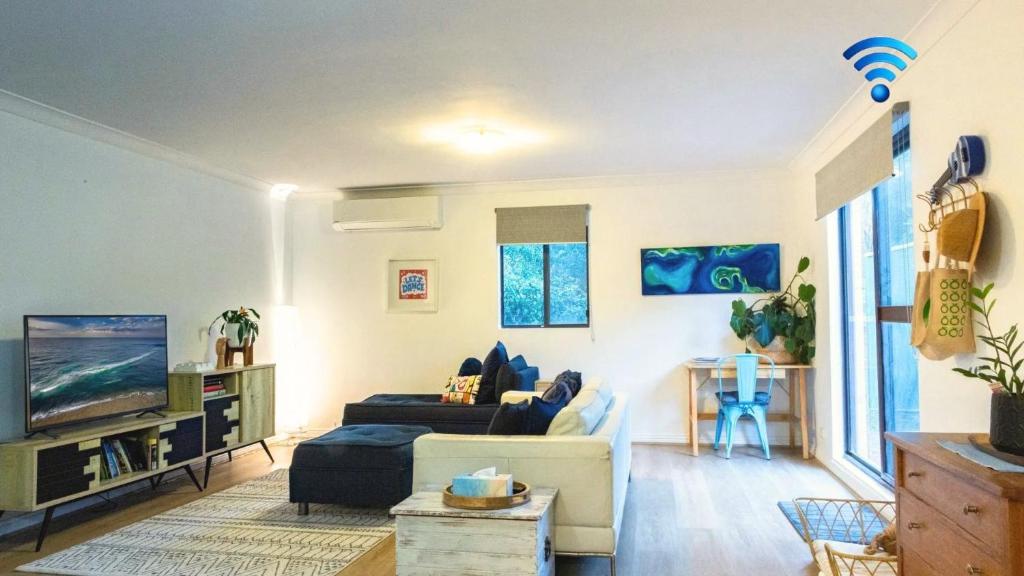 a living room with a couch and a tv at Gidgets on Gretel in Nelson Bay