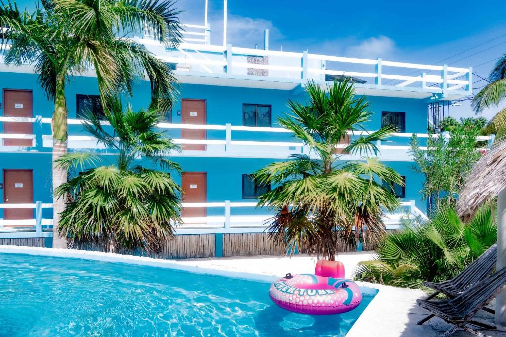 a pool in front of a blue building with palm trees at Affordable Suite with WiFi Partial AC Shared Rooftop Deck Pool and Grill in Caye Caulker