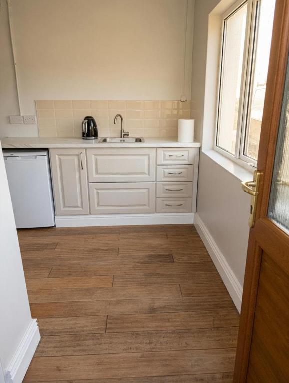 a kitchen with white cabinets and a sink and a window at Dunmore East Studio in Rathmoylan