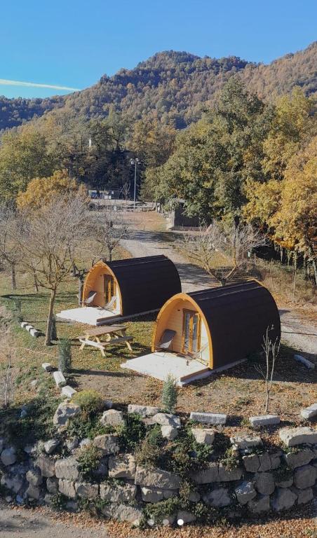 two small tents in a field with a mountain at Camping Vidrà in Vidrá