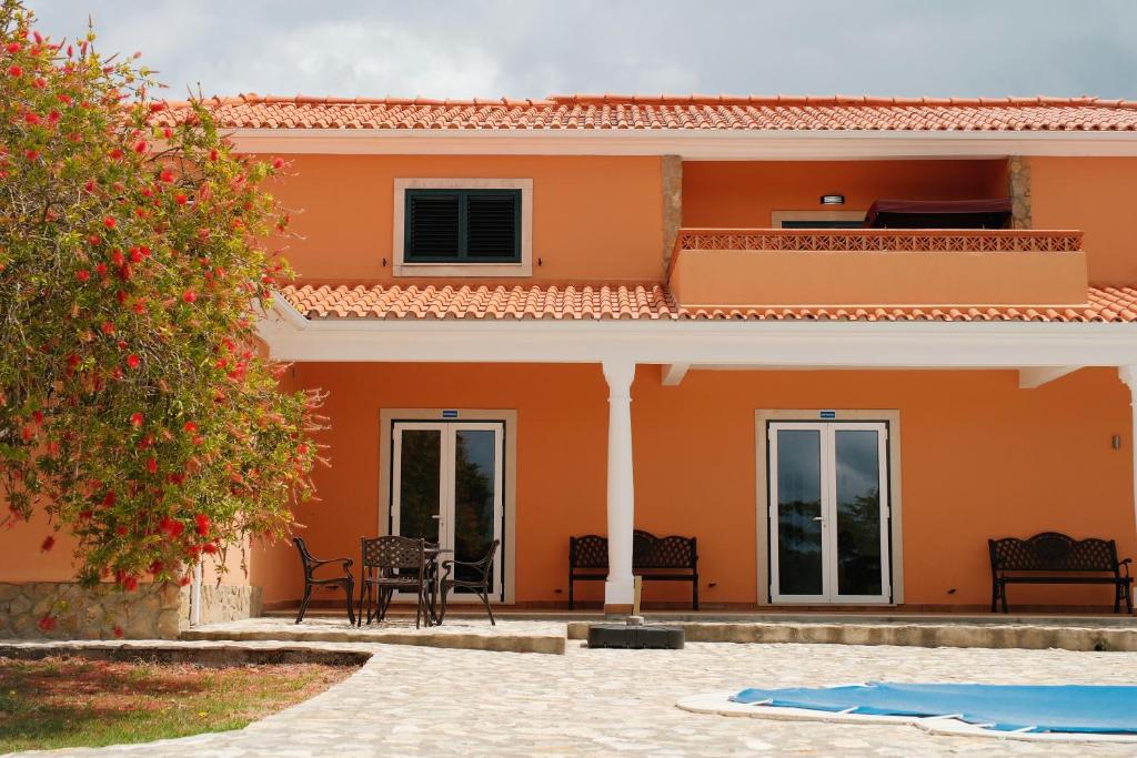 an orange house with a patio and a tree at Quinta da Shambhala in Soriço