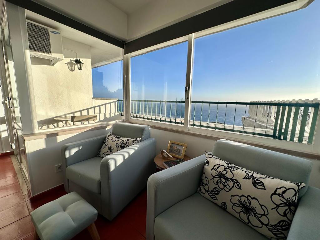 a living room with a couch and chairs and a balcony at Santiago Oceanfront Living in Sesimbra