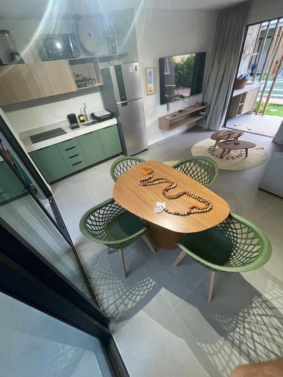 a kitchen with a wooden table and some chairs at Villa Maui - Milagres in Passo de Camarajibe