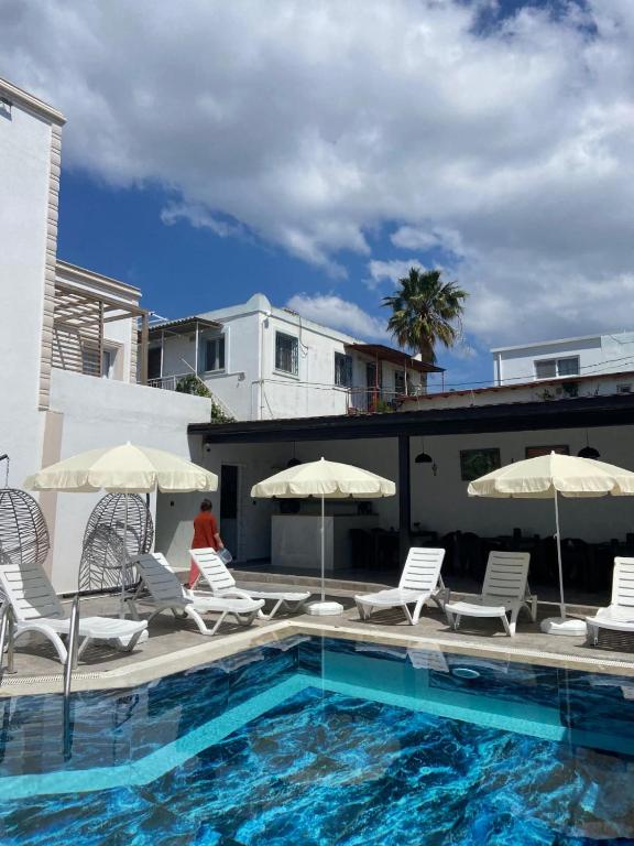 a swimming pool with chairs and umbrellas next to a building at Ydora Luxury Hotel in Bodrum City