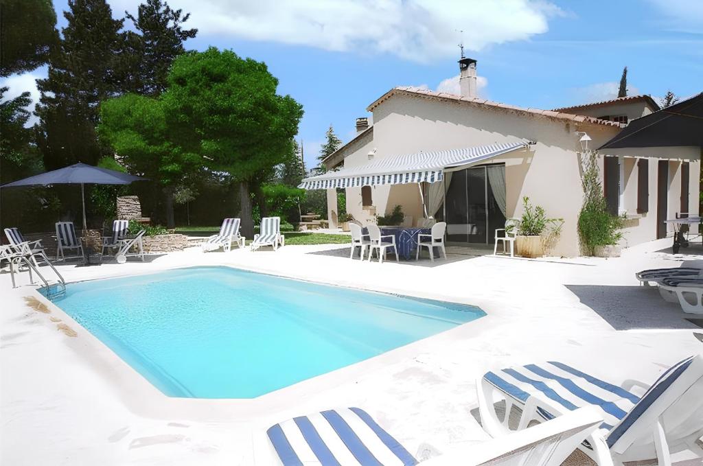 a swimming pool with chairs and a house at Villa élégante à Céreste avec piscine privée et jacuzzi in Céreste