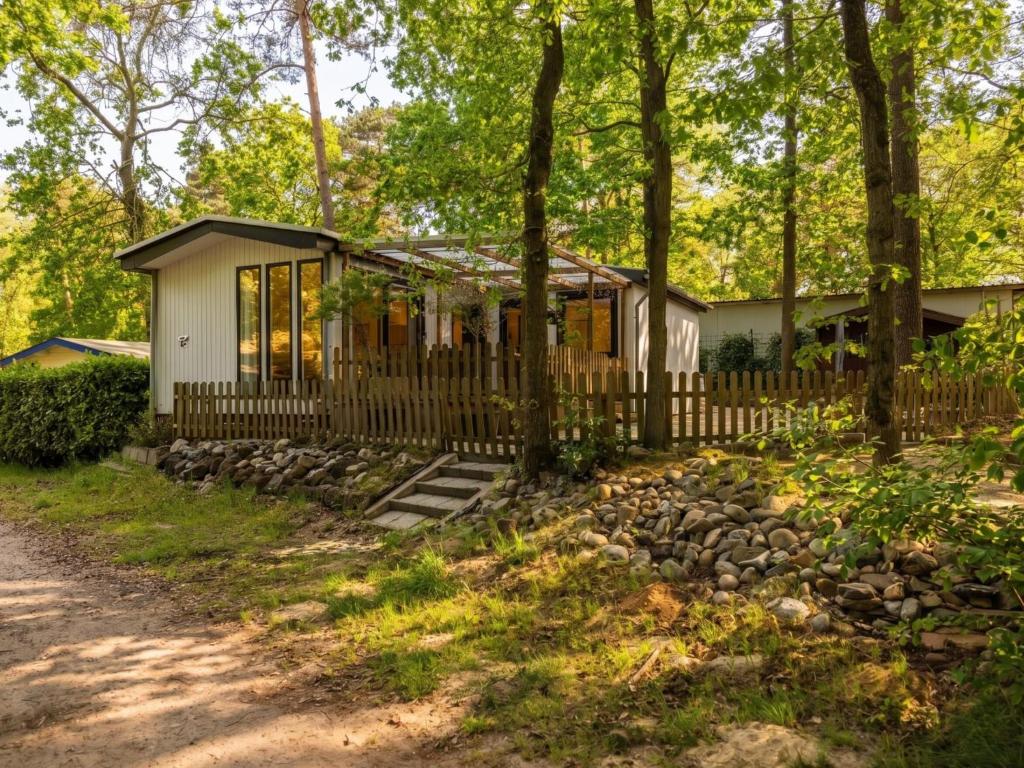 a cottage in the woods with a fence at Villa Fox in IJhorst