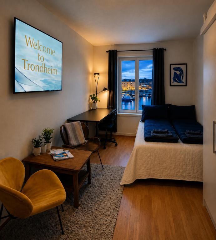 a bedroom with a bed and a desk and a window at Central-Trondheim Riverside Studio-Apartment in Trondheim