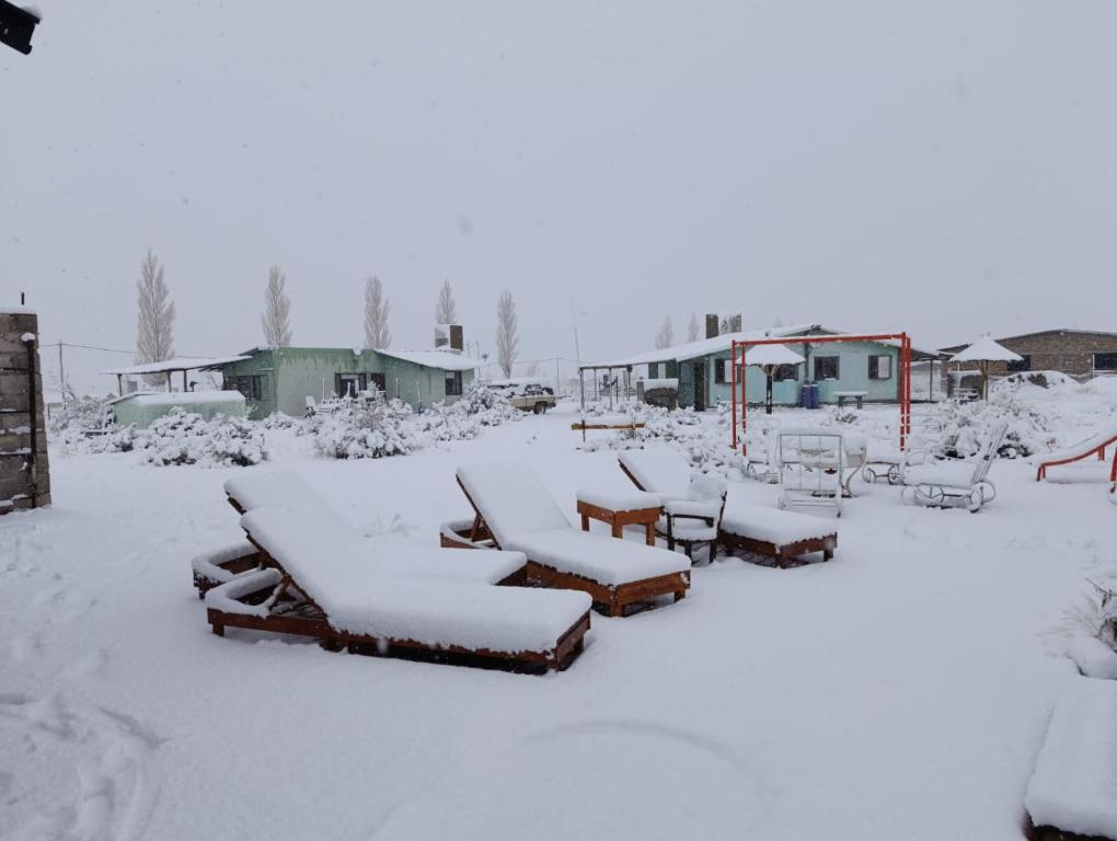 a yard covered in snow with tables and benches at La Chakana in Uspallata