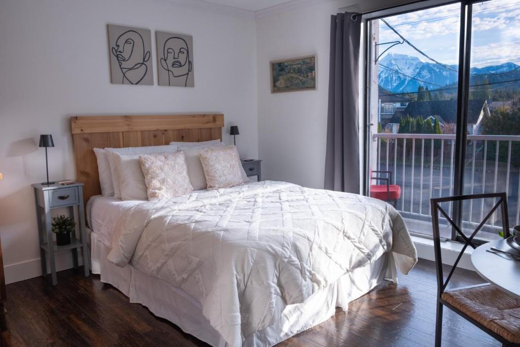 a bedroom with a bed and a large window at Wanderlust Studio Suite with Private Patio in Harrison Hot Springs