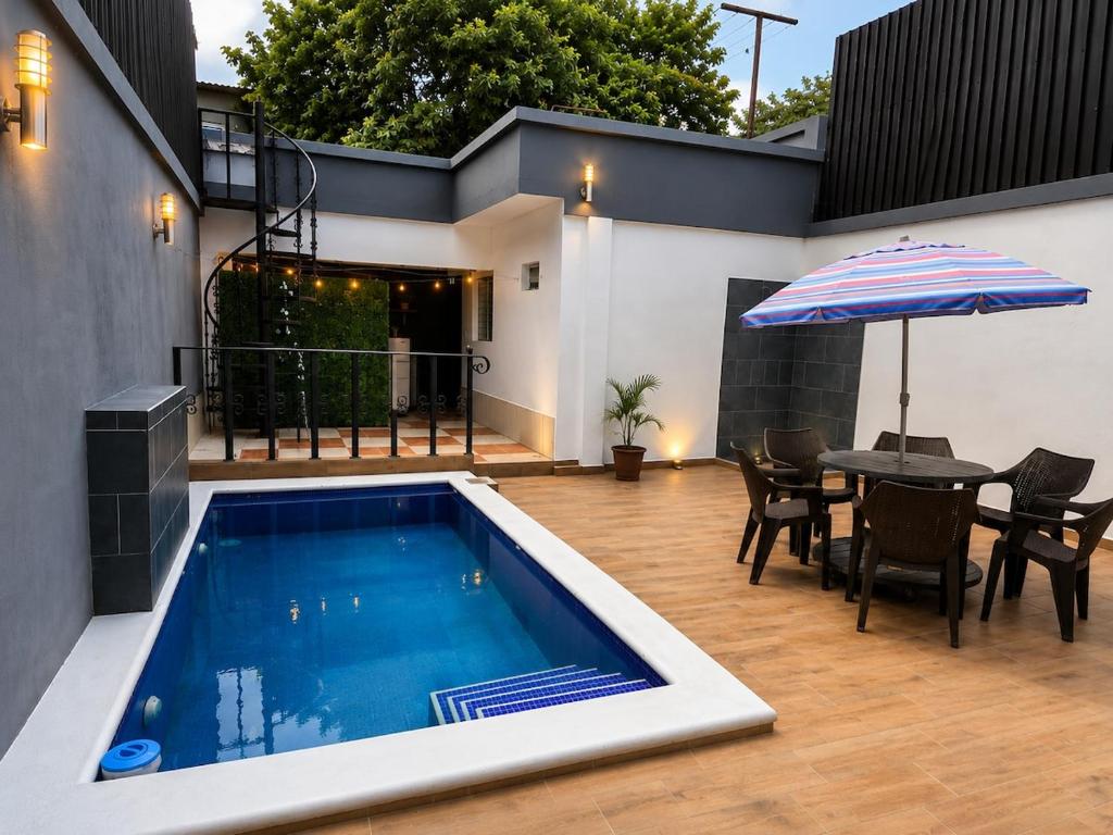a swimming pool with a table and an umbrella at Modern House with Private Pool in Santa Rosa de Copán