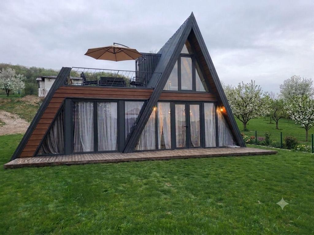 a house with a deck with an umbrella on the grass at Breeze Cabin كوخ النسيم in Ilijaš