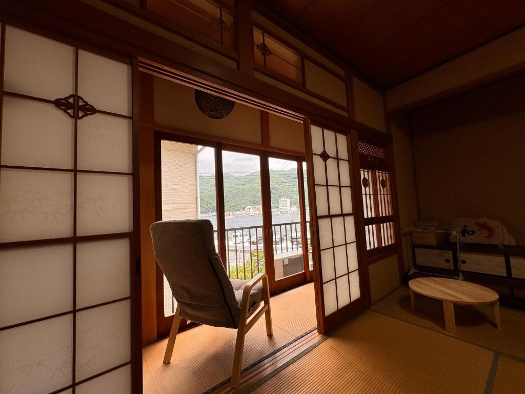 a living room with a chair and a balcony at Calmbase西伊豆いざよい in Numazu