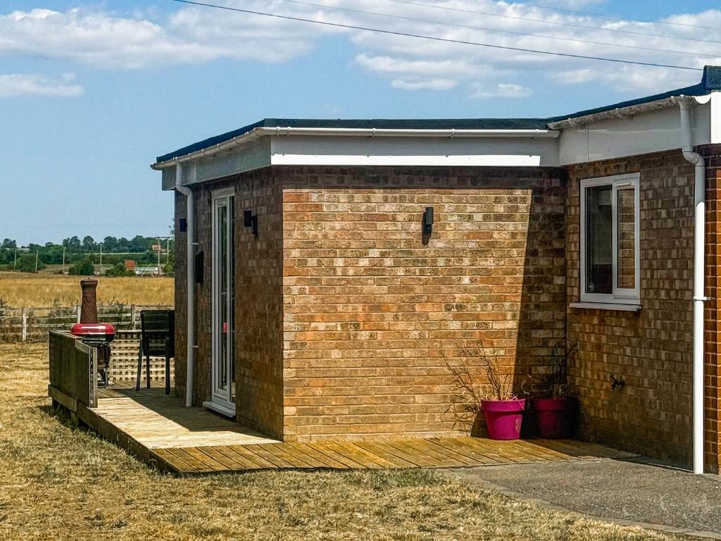 a small brick building with a porch on a field at Jubilee Farm Cottage in Washingborough