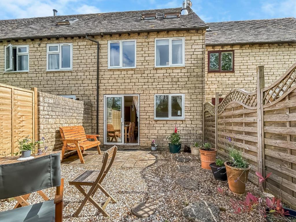 a home with a wooden fence and a patio at Rose Cottage in Upper Rissington