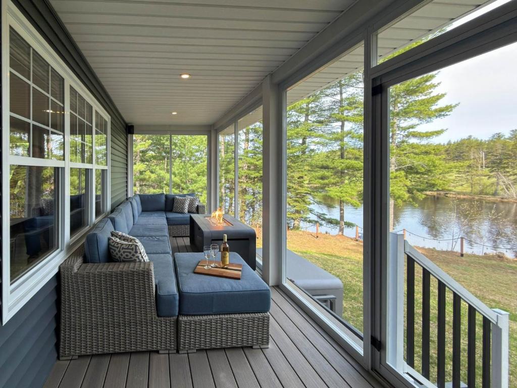 a screened in porch with a couch and chairs on it at Riverside Retreat in Rexton