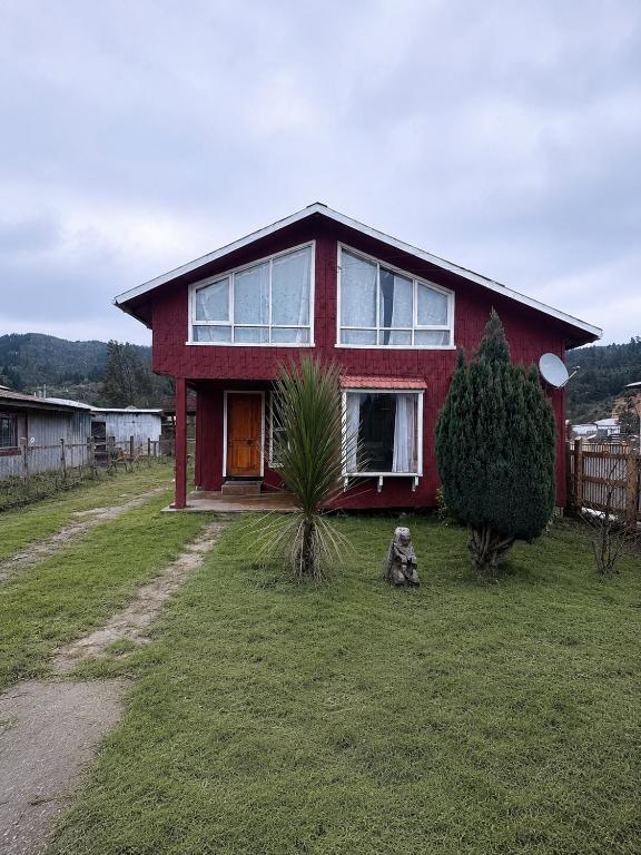 a red house with a dog sitting in front of it at Casa familiar Queule in Queule