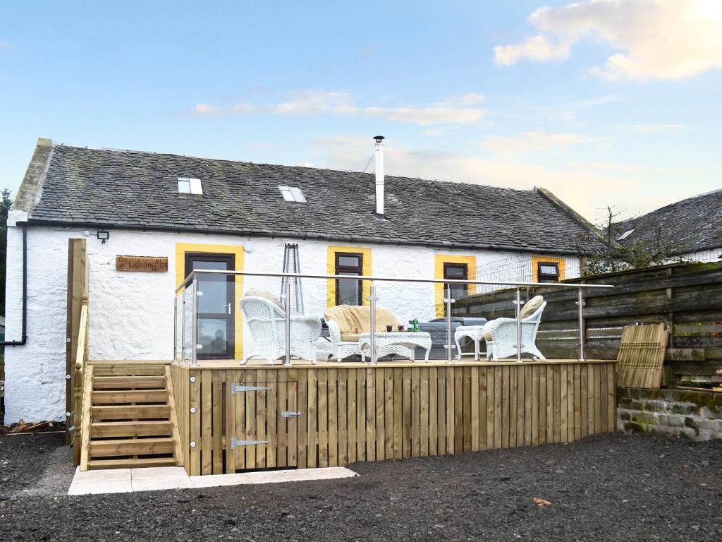 a white house with a wooden fence in front of it at The Calving Shed in Neilston