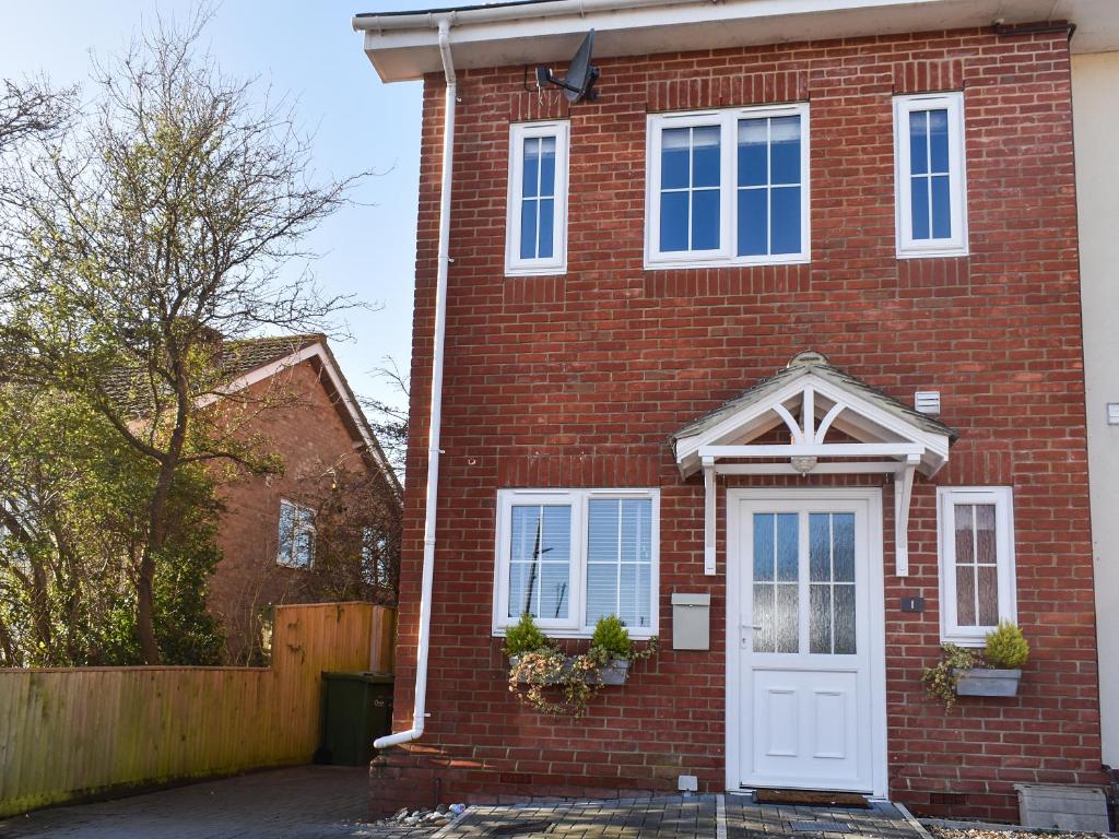 a red brick house with a white door at Coed Faen in Saint Helens