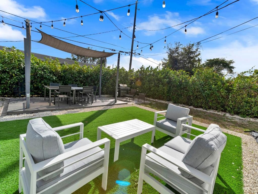 a patio with two white chairs and a table at Casa Playa Coastal Comfort 10 Min From Beach in Hallandale Beach