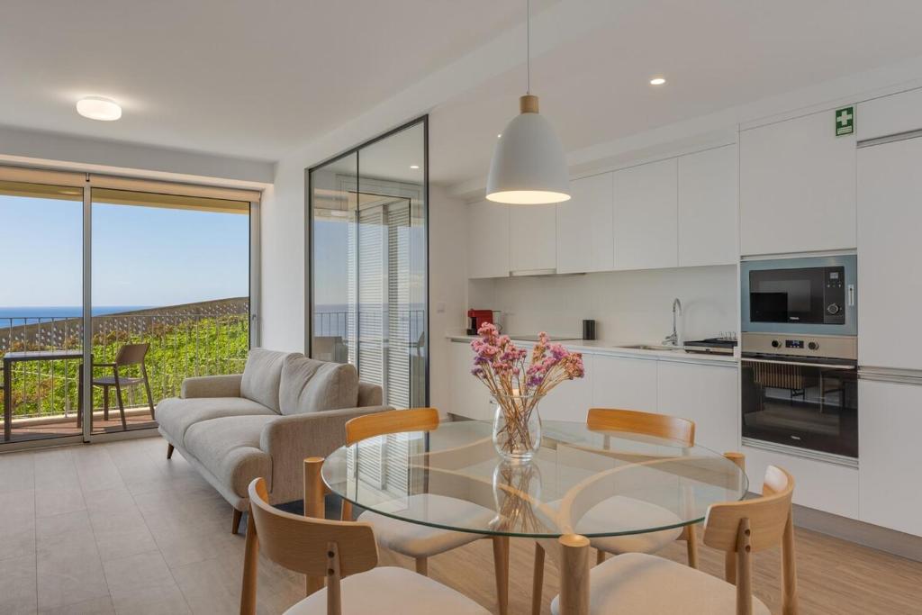 a kitchen and a living room with a glass table at Pool Retreat For Families & Romantic Escapes in Câmara de Lobos