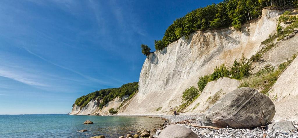 einen felsigen Strand neben einer großen weißen Klippe in der Unterkunft Bernstein Appartements in Dranske