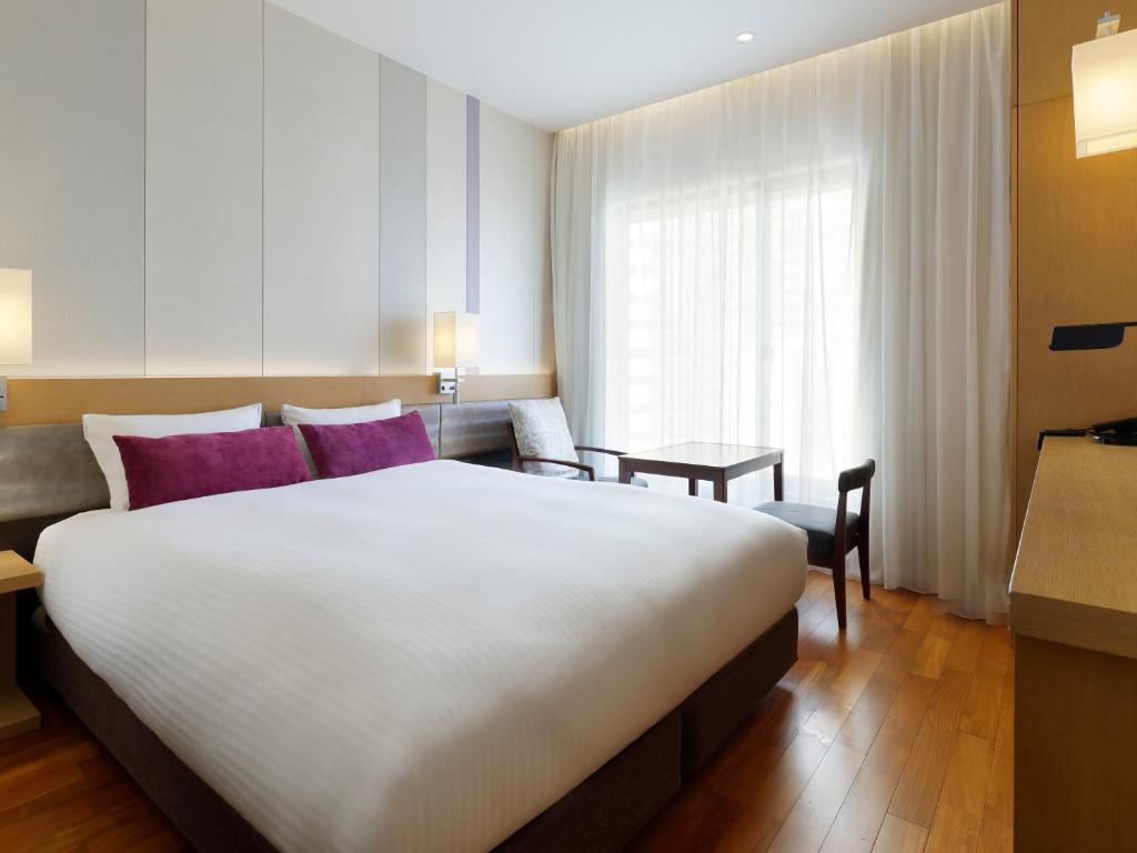 a hotel room with a large white bed and a window at Mitsui Garden Hotel Osaka PREMIER in Osaka